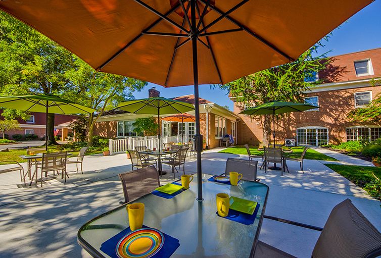 A sunny outdoor patio area with tables, chairs, and large umbrellas.