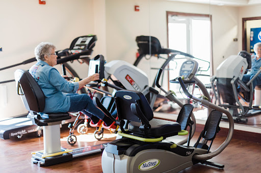 An elderly individual engaging in physical activity on a recumbent bike at a fitness center.