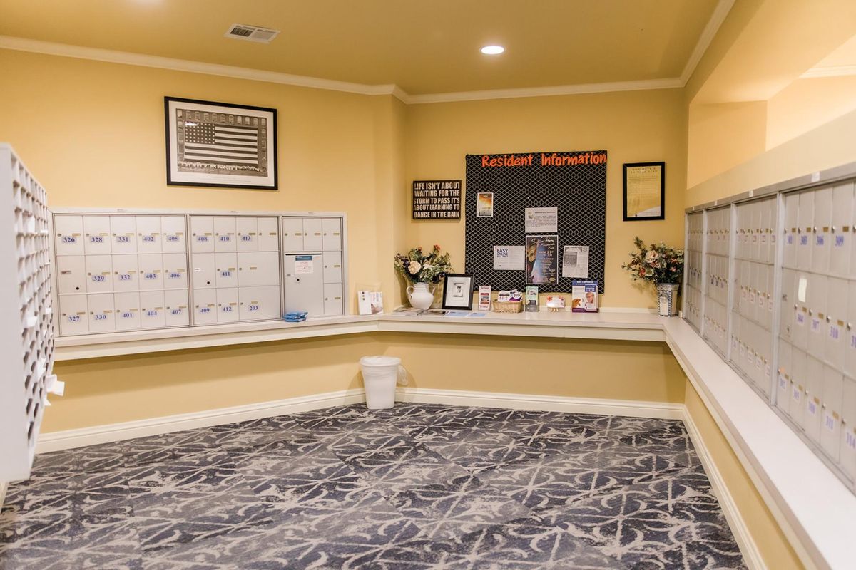 A tidy apartment mailroom with mailboxes and a community notice board.