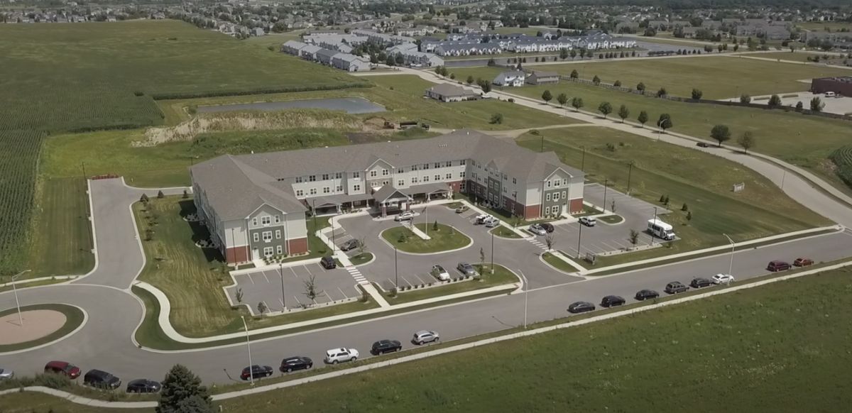 Aerial view of a suburban building complex with surrounding parking area and roads.