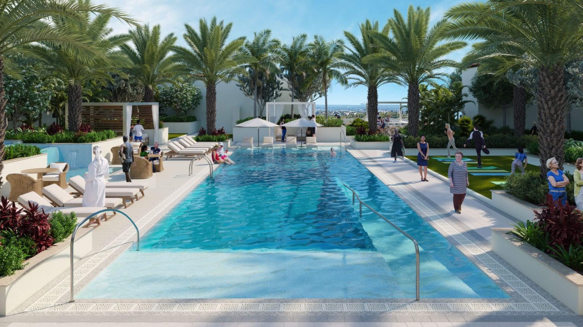 A luxurious outdoor swimming pool area at a resort with palm trees and clear blue skies.