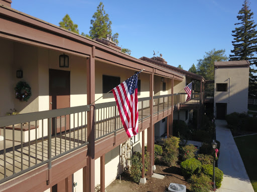 An American flag displayed on a balcony of an apartment complex under a clear blue sky.