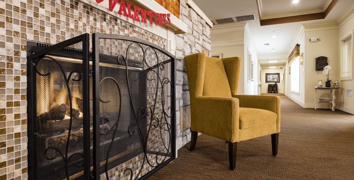 A cozy living room setting with a yellow wingback chair by the fireplace.