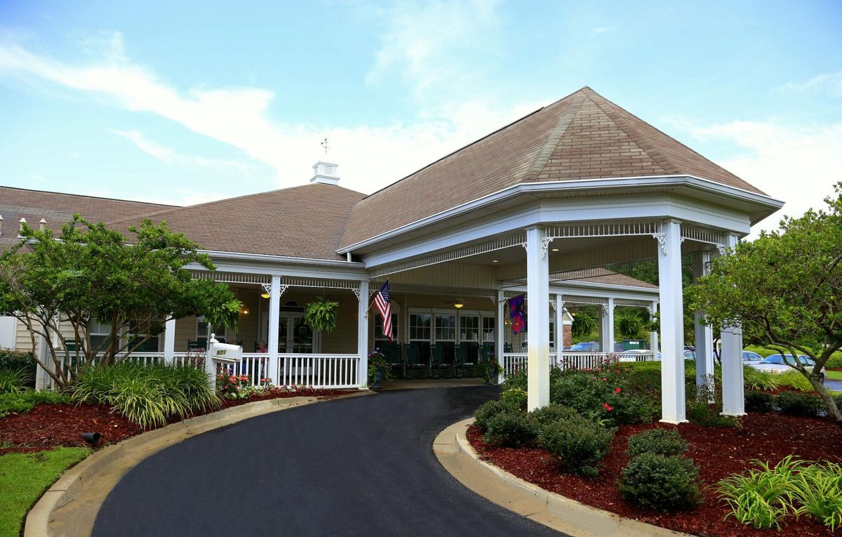 A picturesque residential building with a covered entrance and landscaped driveway.