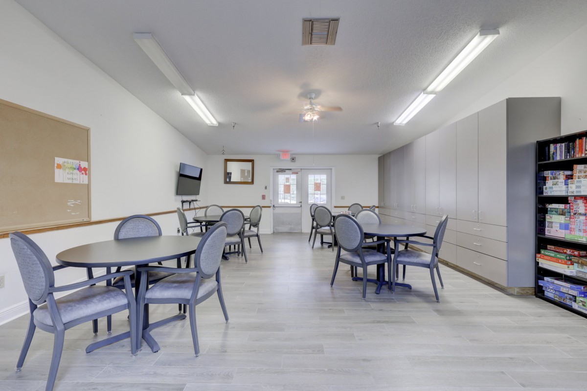 An empty, well-lit room with tables and chairs arranged neatly.