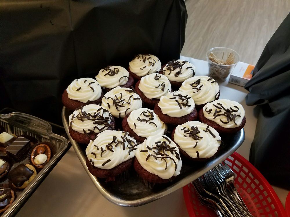 A tray full of delicious cupcakes topped with frosting and chocolate shavings.