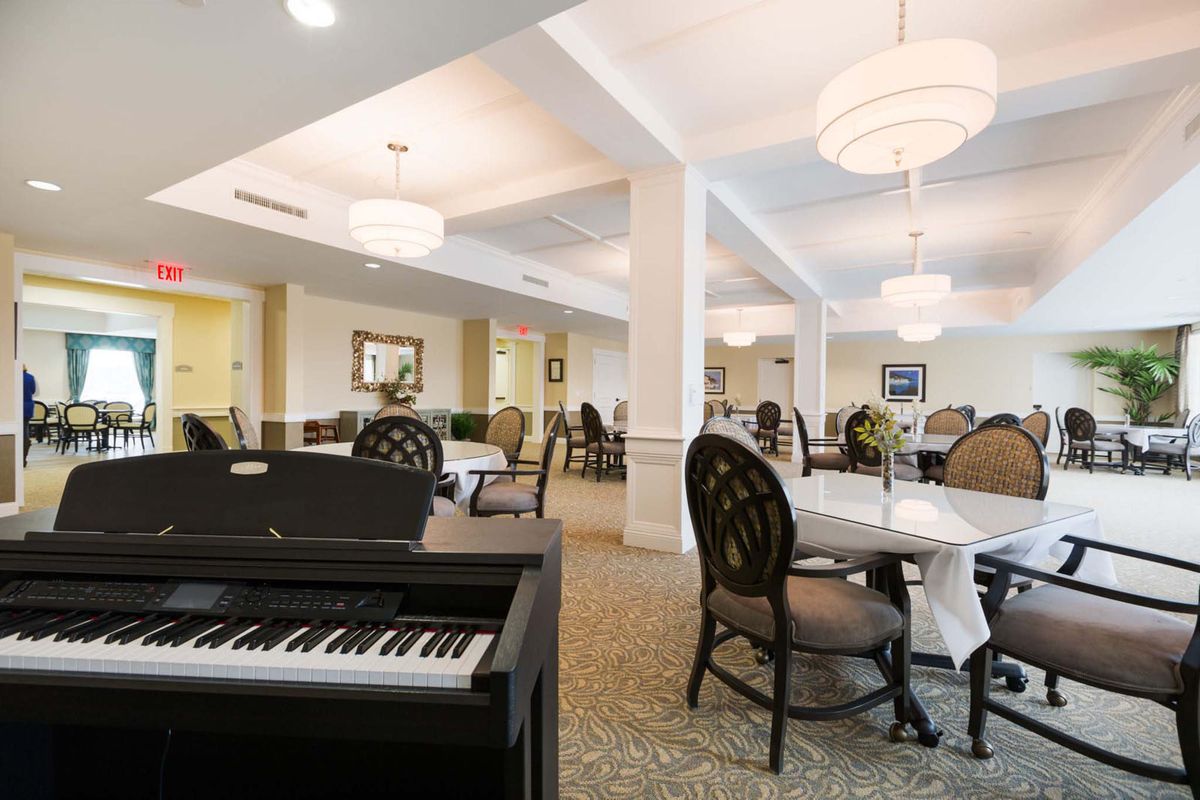 A spacious dining area with elegant furnishings and a piano in the foreground.