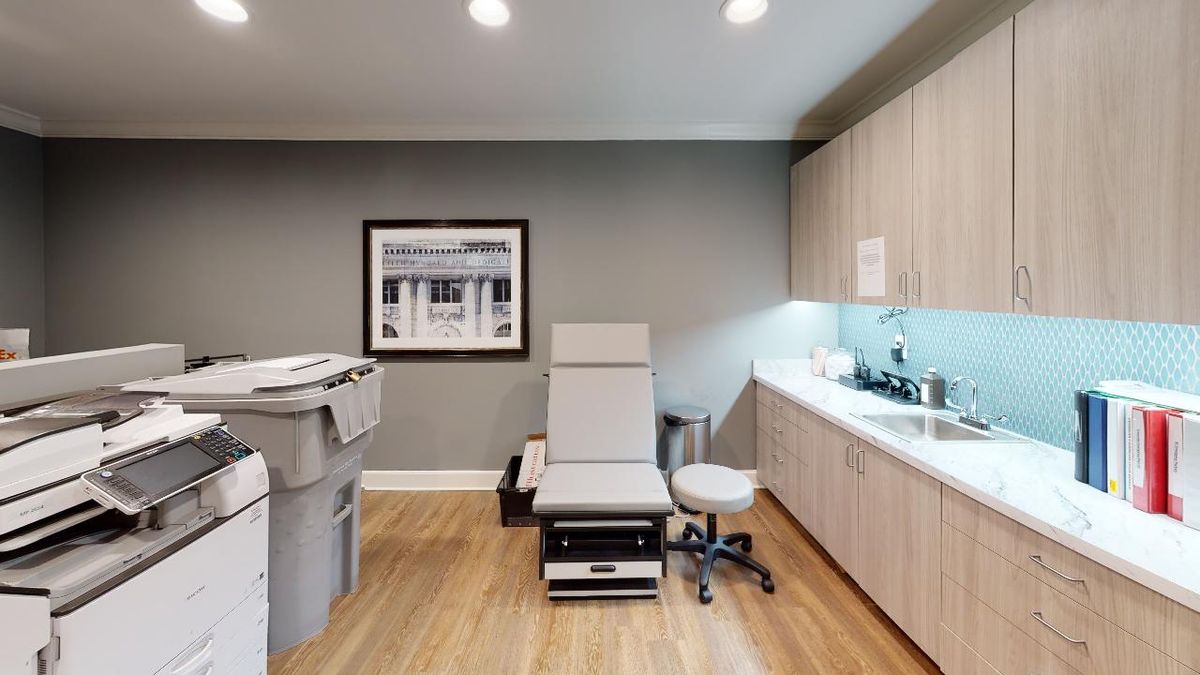 A clean and modern medical examination room with an exam chair and healthcare equipment.