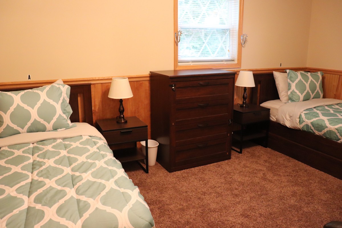 A cozy bedroom with two twin beds, a dresser between them, and bedside lamps.