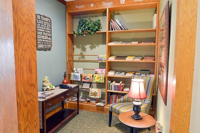 A cozy reading nook features a bookshelf filled with books and magazines, accompanied by a comfortable chair and a lamp for ambient lighting.