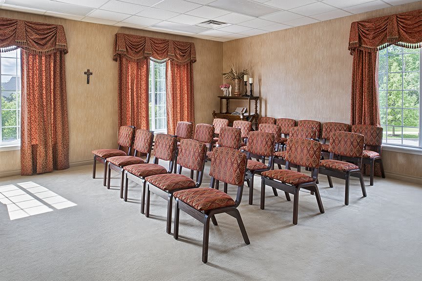A small, intimate room set up with rows of chairs and a shelf decorated with candles.