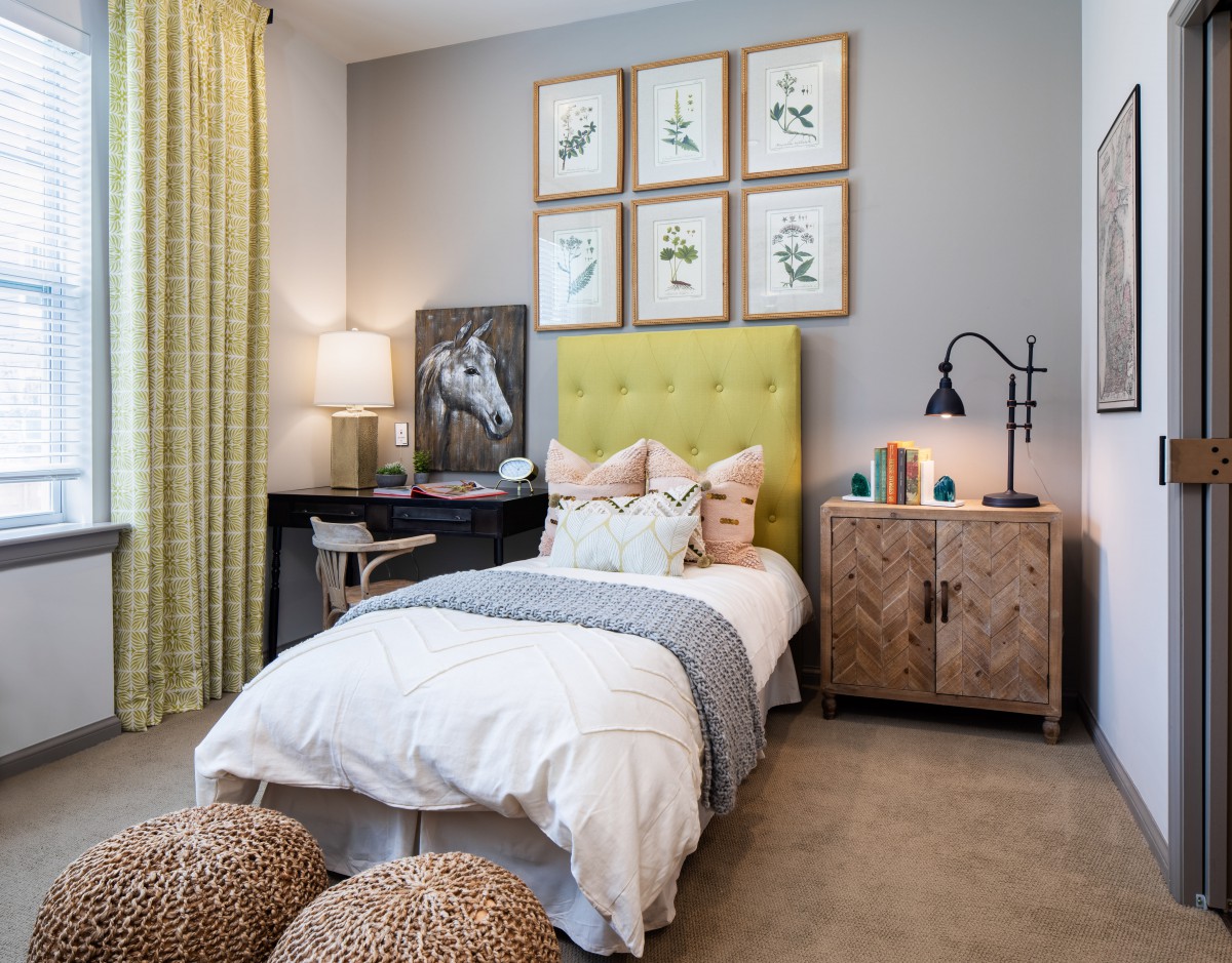 A stylishly decorated bedroom with a single bed, colorful headboard, and nature-themed artwork.
