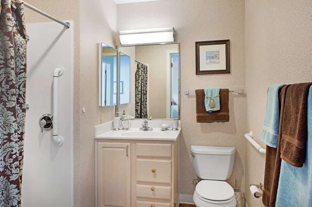 A compact bathroom with a shower, toilet, and sink equipped with a mirror and storage cabinet.