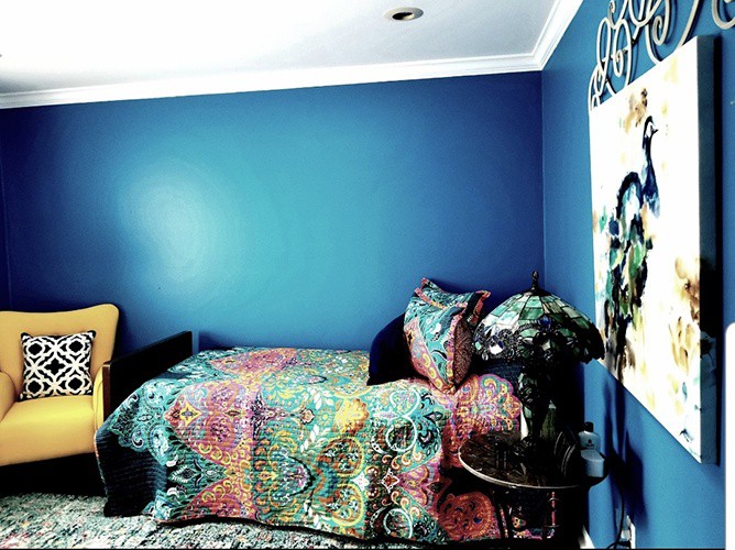 A cozy bedroom with vibrant, colorful bedding against deep blue walls.