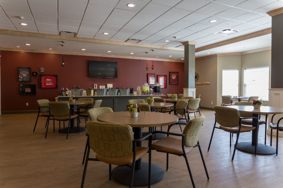 A modern cafe with a spacious seating area, featuring round tables and comfortable chairs.