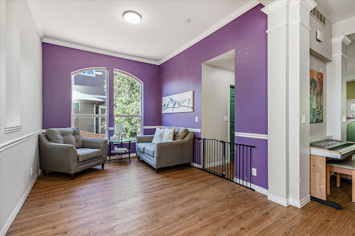 A bright and stylish living room featuring elegant purple walls and comfortable seating.