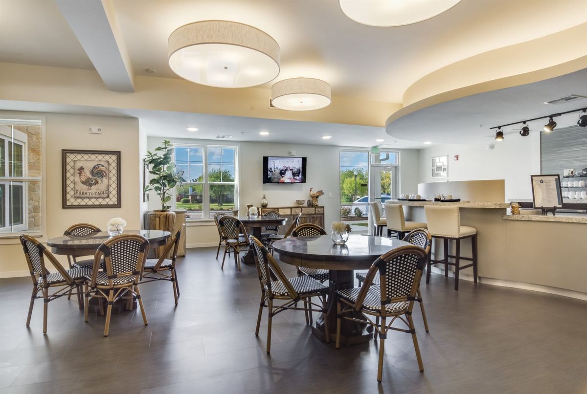 A modern dining area with tables and chairs, featuring large windows and contemporary lighting.