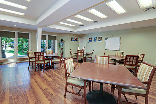 A communal dining area with wooden floors and multiple tables and chairs.