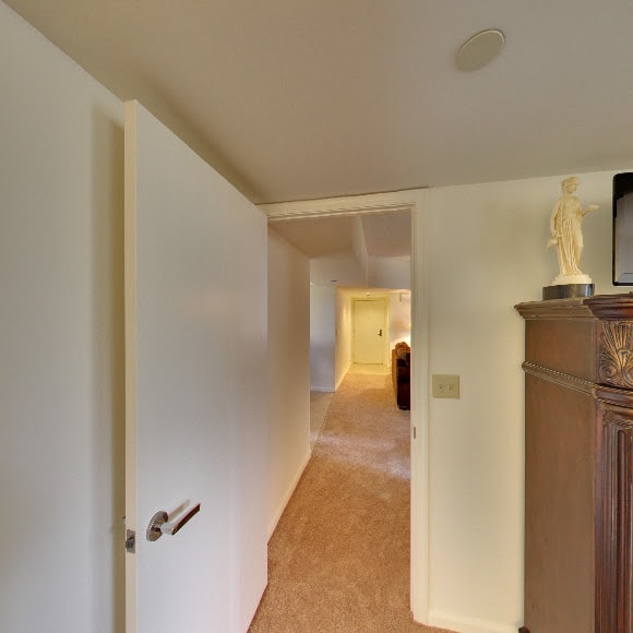 View of a hallway with an open door and carpeted floor.