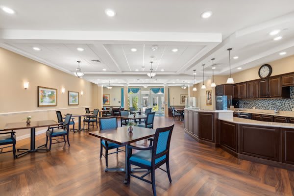 A spacious dining area with tables, chairs, and a view of the kitchen.