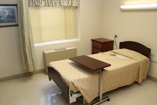 A clean and tidy hospital room with a bed, nightstand, and window.