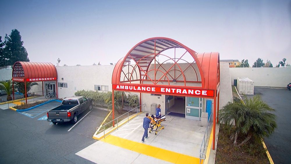 Medical staff wheel a stretcher into the ambulance entrance of a hospital.