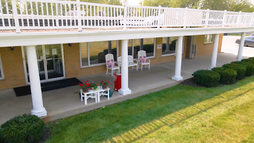 A serene outdoor patio area with white furniture and a view of the lawn.