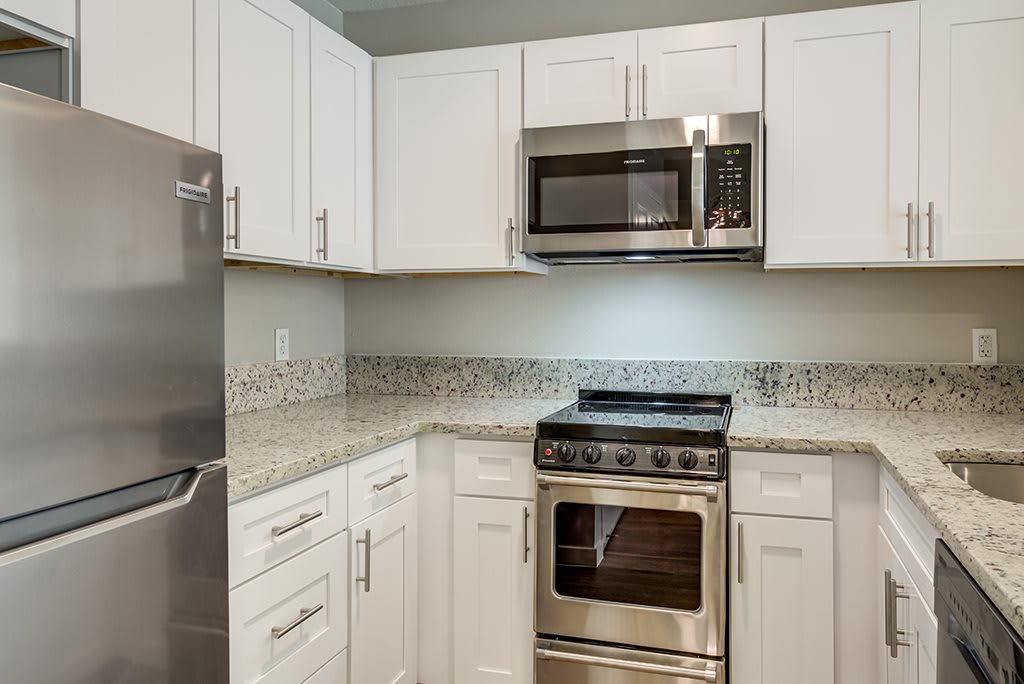 Modern kitchen with white cabinets and stainless steel appliances.