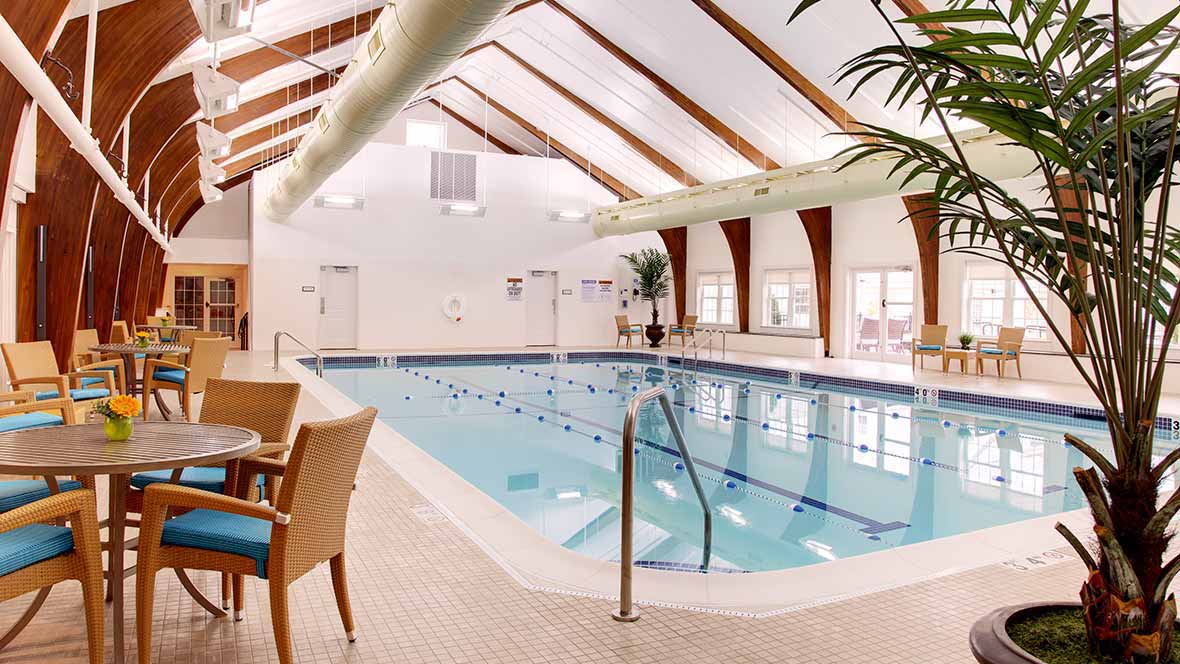 A spacious indoor swimming pool with seating and bright natural lighting.