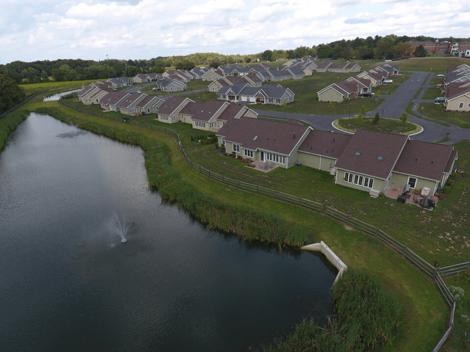 Aerial view of a suburban residential area with houses lining a small lake.