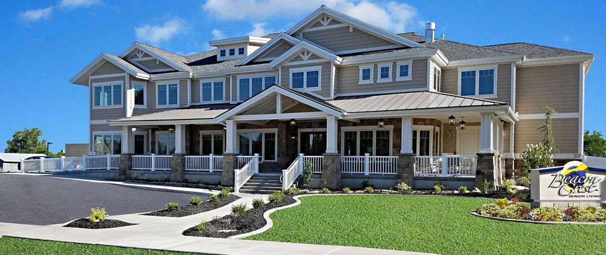 A large, modern house with a spacious porch and well-maintained lawn.