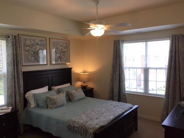 A cozy bedroom with a bed, bedside lamp, and large window.