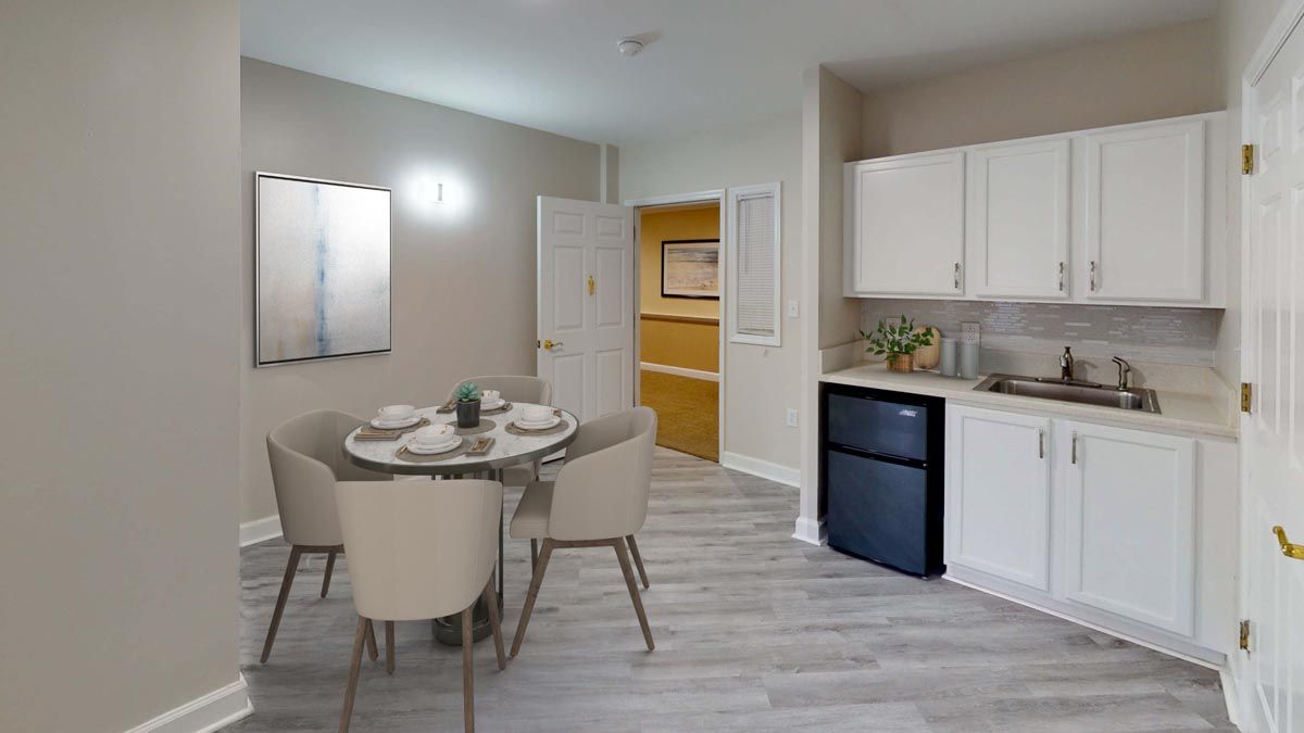 A modern dining area with a small kitchenette, featuring a round table set for four.