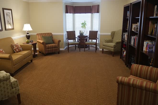 A cozy living room with comfortable chairs, a carpeted floor, and a large window.