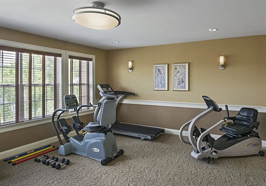 A small home gym with various fitness equipment including a treadmill, exercise bike, and elliptical machine.