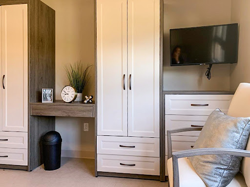 A modern home office setup featuring a sleek desk, storage cabinets, and a television.