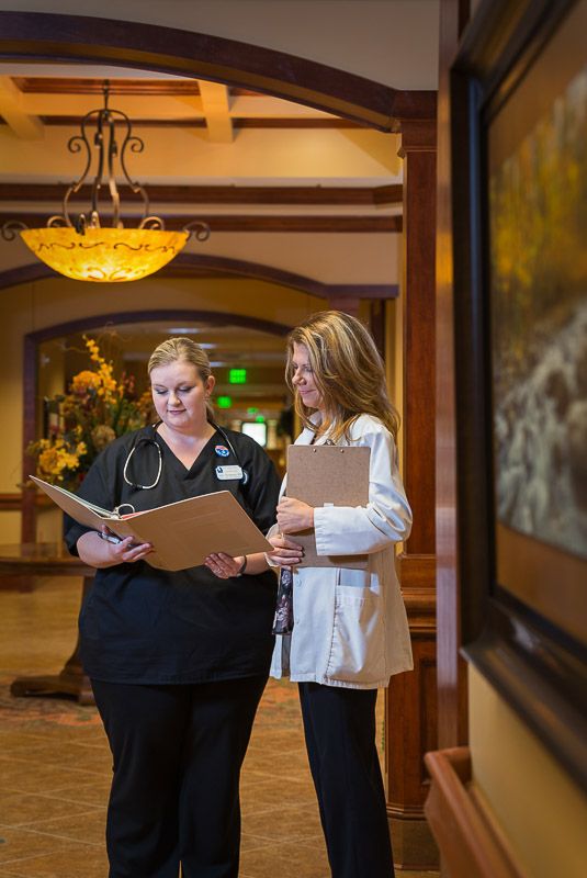 Two healthcare professionals discussing patient information in a hospital corridor.