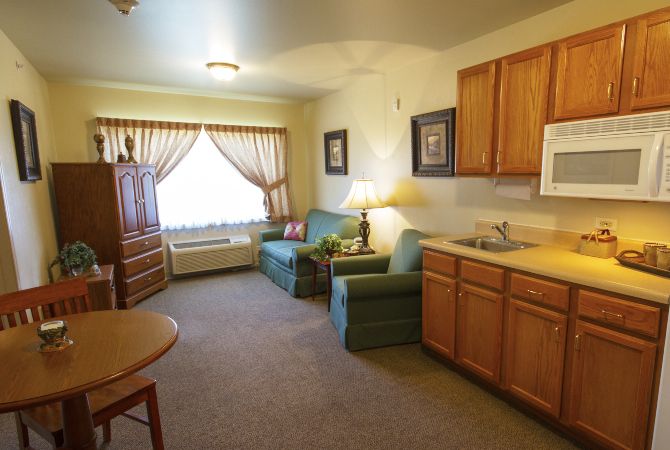 A cozy apartment living room with a kitchenette, featuring comfortable seating and warm decor.