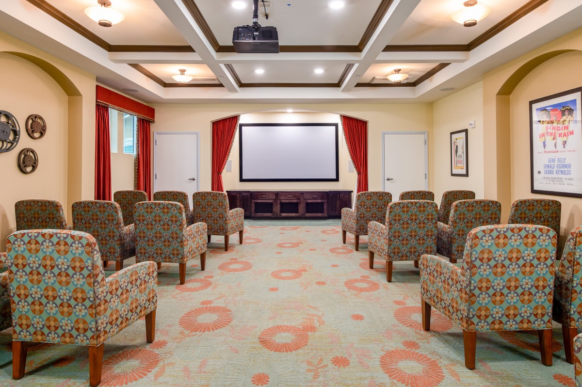 A cozy home theater with arranged seating facing a large screen and projector.