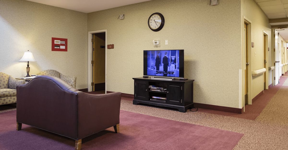 A cozy living room with a television, sofa, and wall clock.