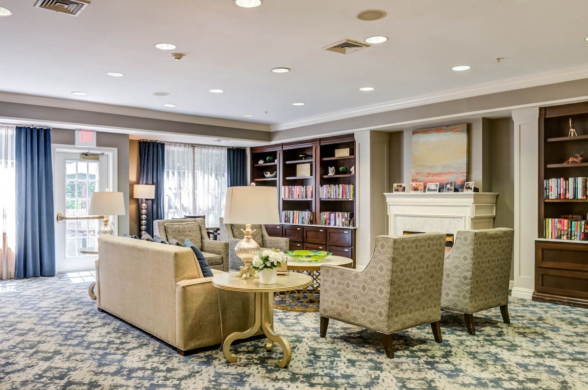 A cozy living room area with armchairs, a sofa, bookshelves, and a fireplace.