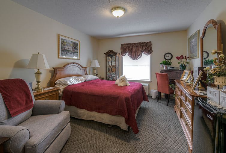 A cozy bedroom with a red bedspread, wooden furniture, and decorative items.