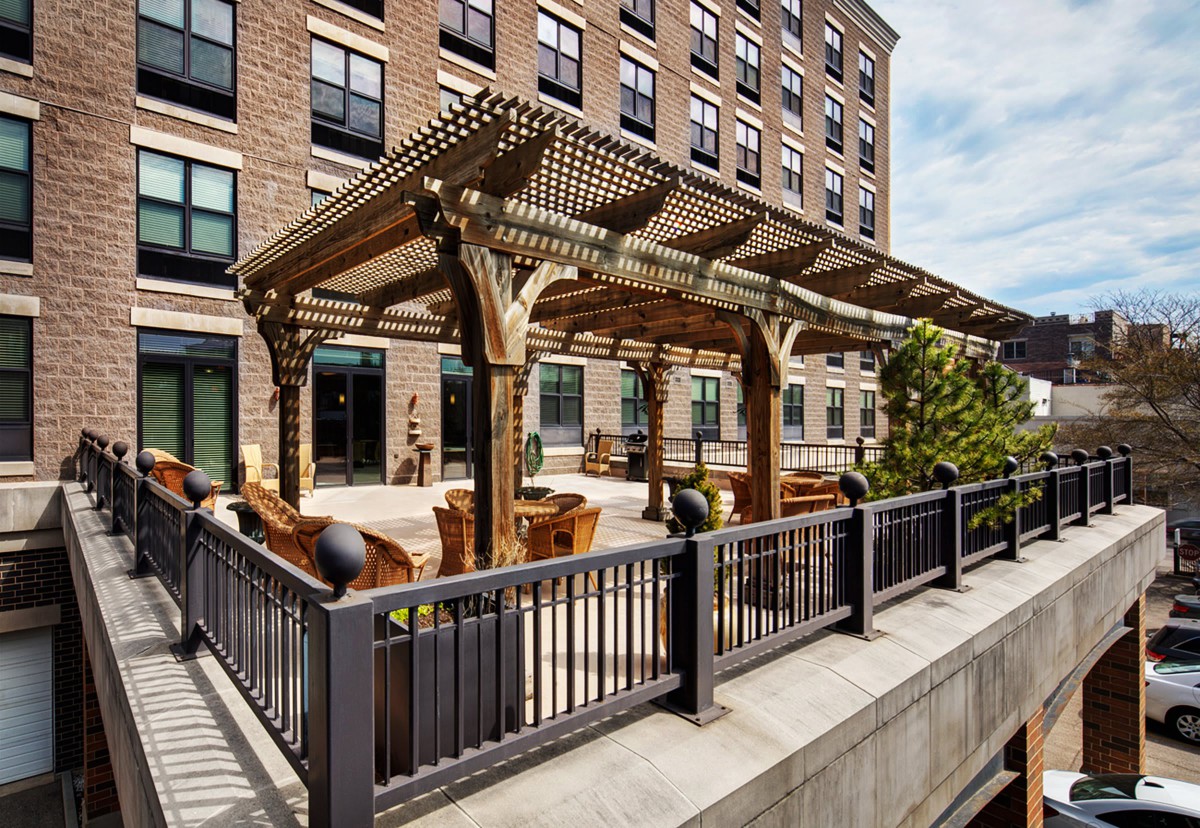 Outdoor seating area with a wooden pergola on a building patio.