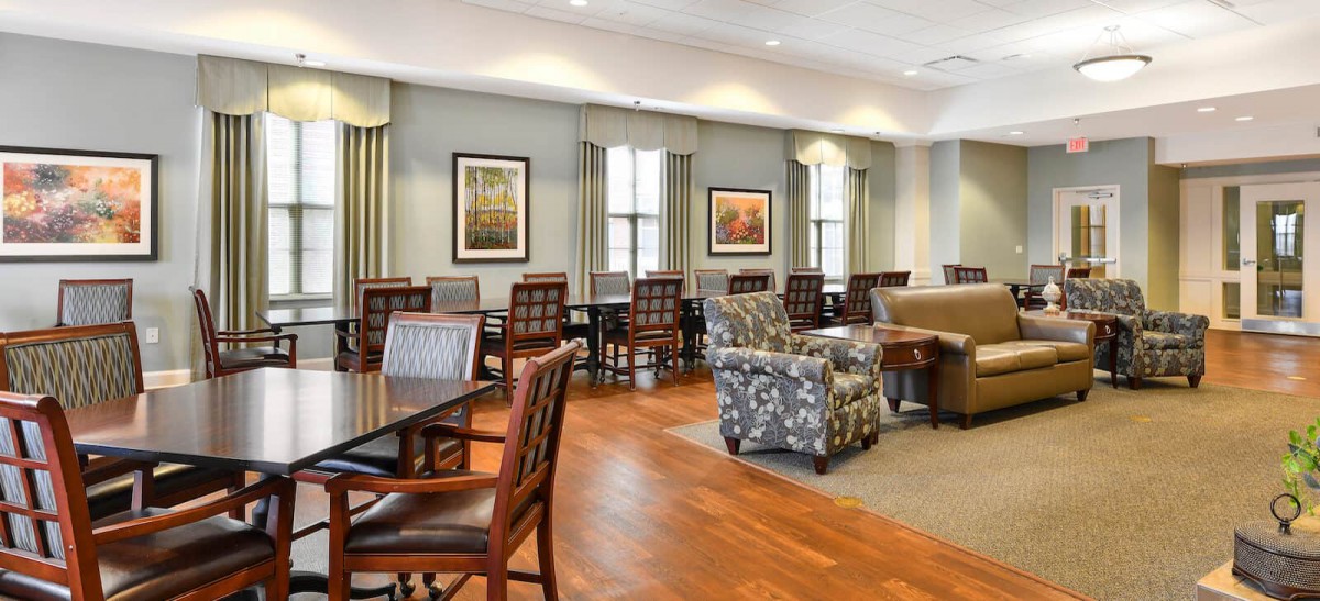 A spacious and well-lit lounge area featuring a mix of tables, chairs, and comfortable seating.