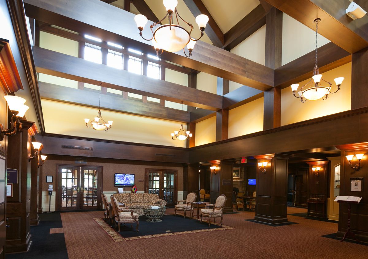 A spacious hotel lobby with elegant chandeliers, wooden beams, and a comfortable seating area.