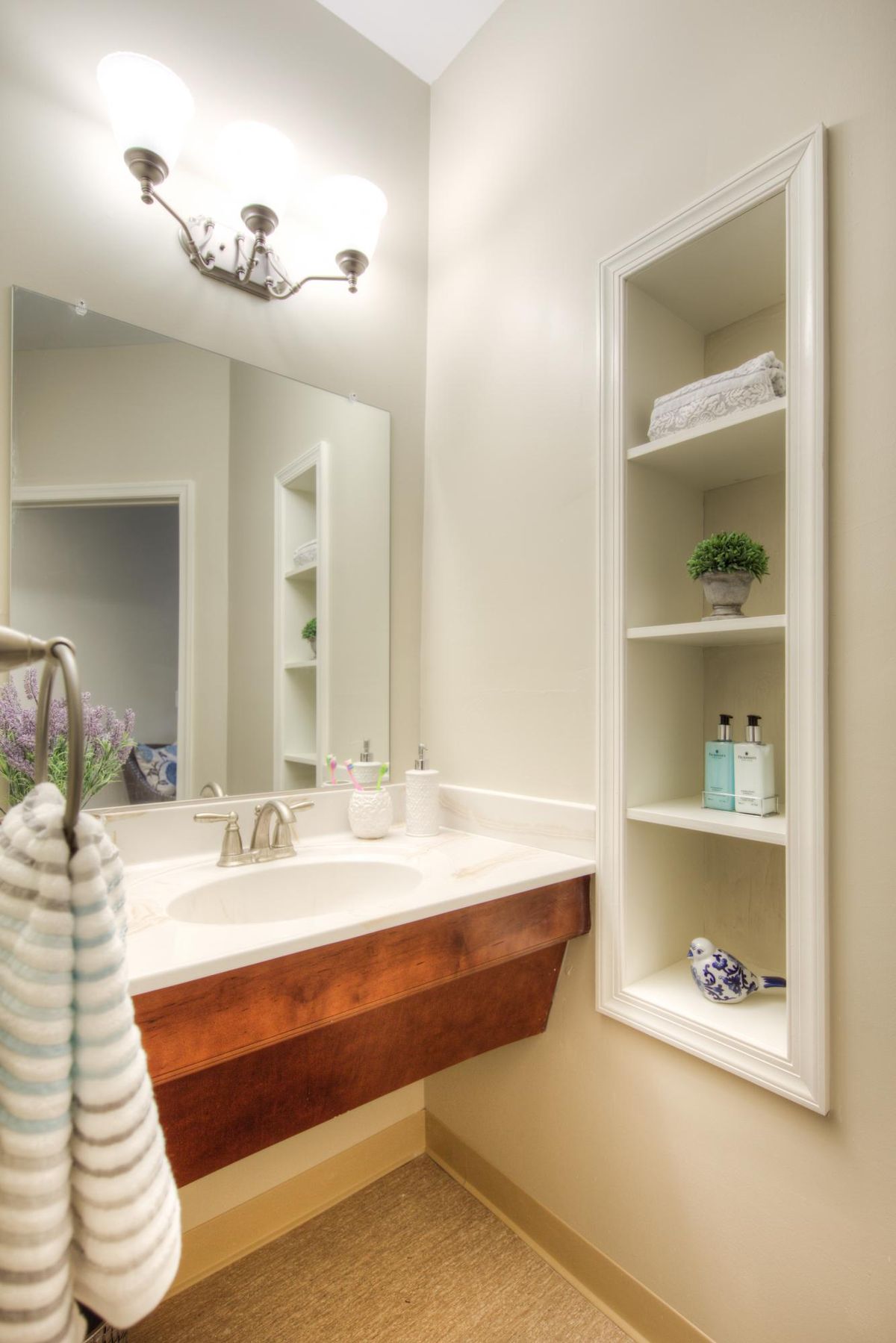 A neatly organized bathroom featuring a sink, mirror, and built-in shelves with decorative items.