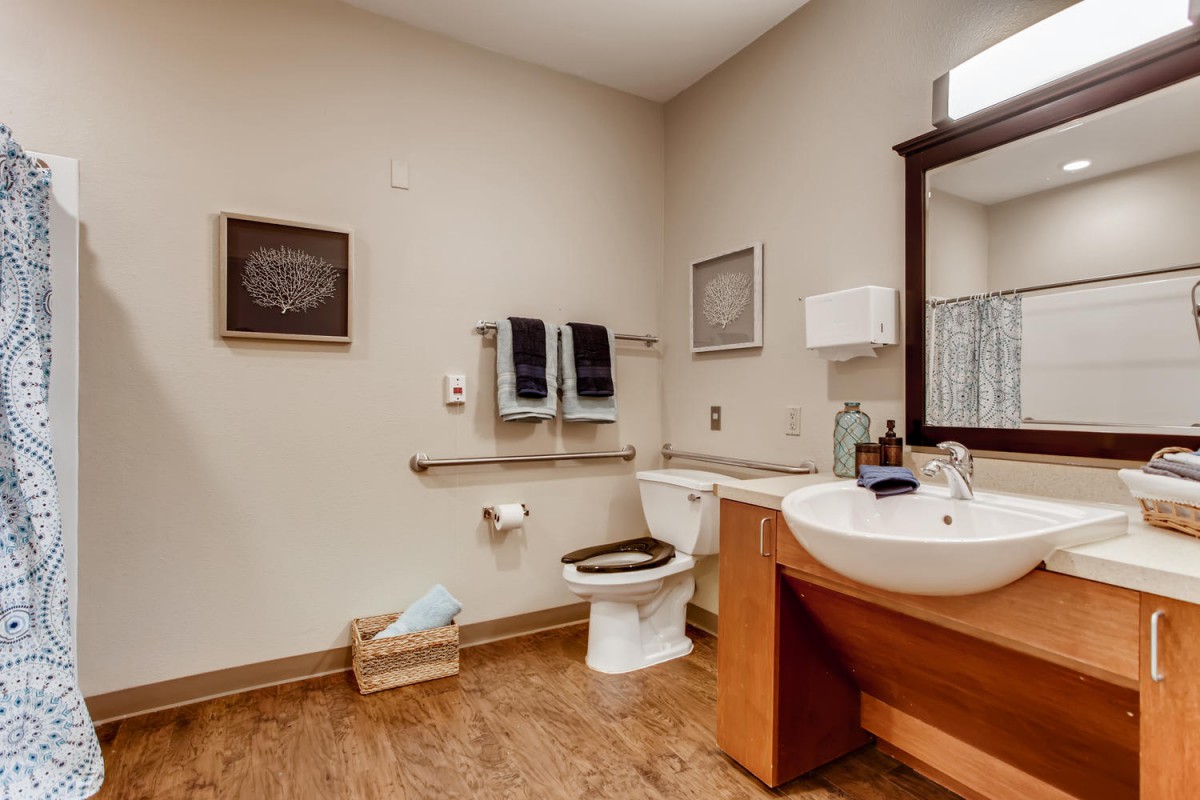 A clean and organized bathroom with a sink, mirror, and toilet.