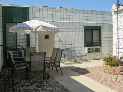 A cozy outdoor seating area with a table, chairs, and an umbrella beside a building.