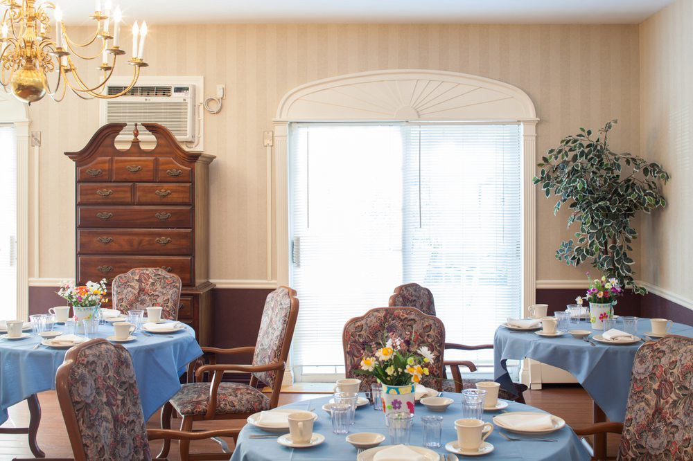 A well-decorated dining room with multiple tables set for a meal, featuring blue tablecloths and elegant chairs.