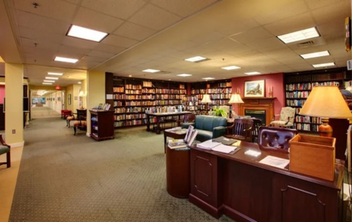 A cozy library interior with bookshelves, a reading area, and a desk.